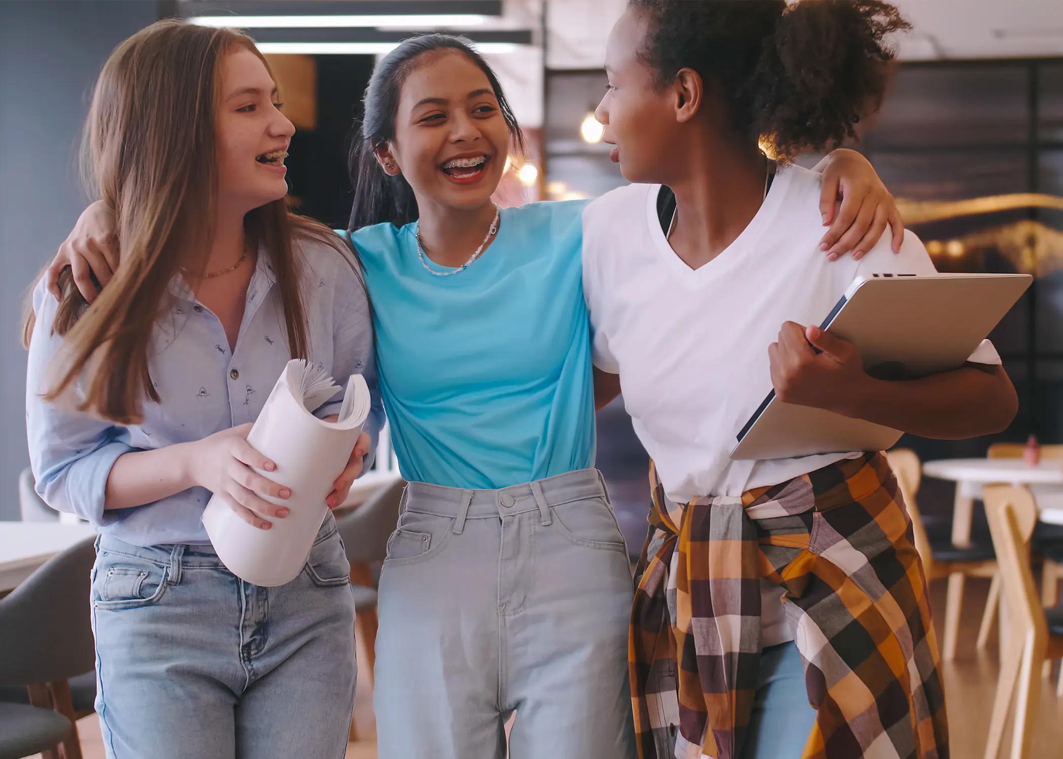 Three female students laughing with their arms around each other